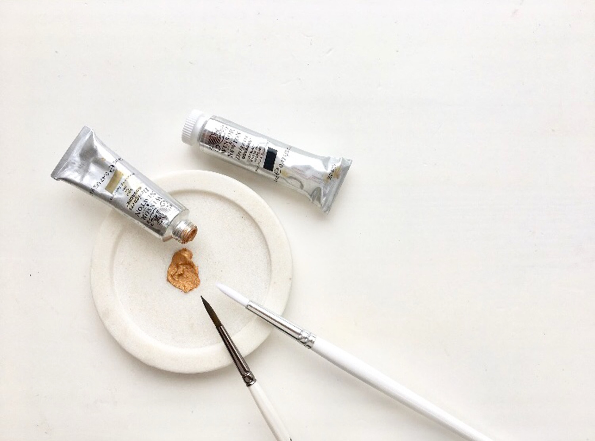 Paint tubes, a brush and a small dish of paint