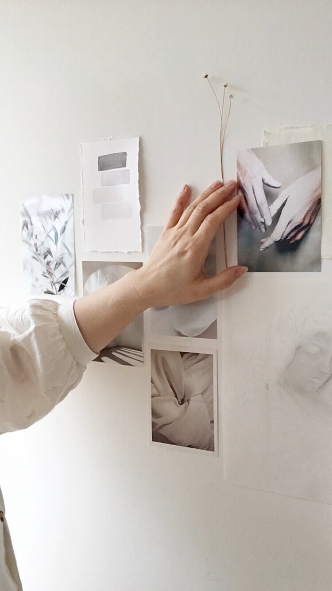 A hand arranging photographs on an inspiration wall