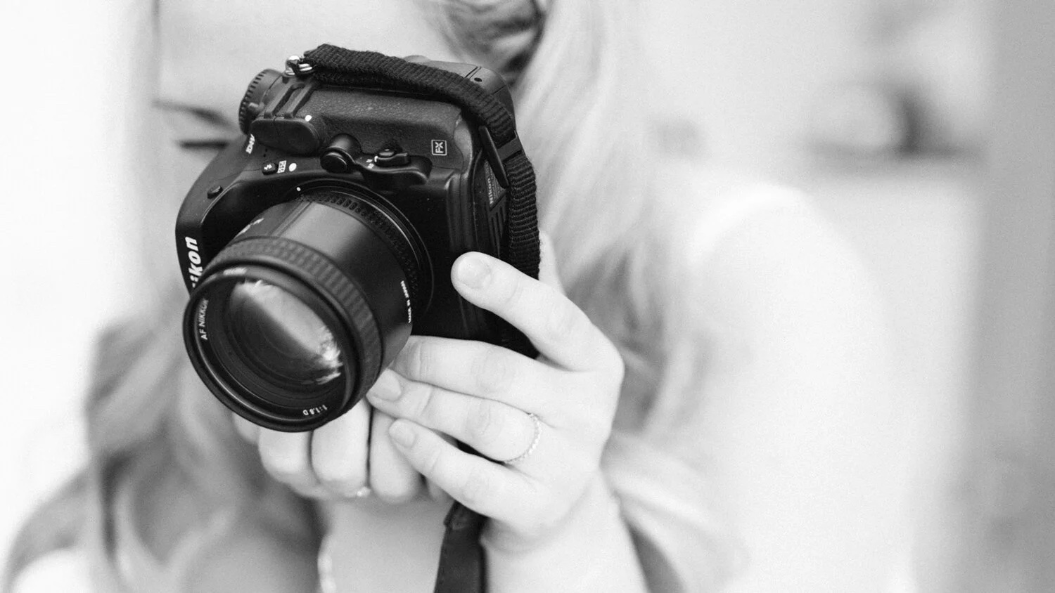 Black and white photo of Kiki holding her camera up to her eye
